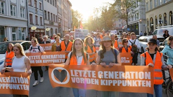 Teilnehmer gehen beim Protestmarsch der Letzten Generation und anderer Klimaschützergruppen nach der Razzia gegen Mitglieder der Klimagruppe in München die Straße entlang.