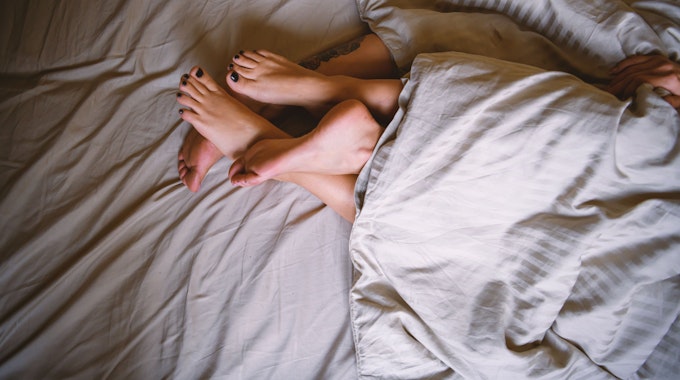 Zwei Paar Füße ragen am Ende einer Bettdecke hervor