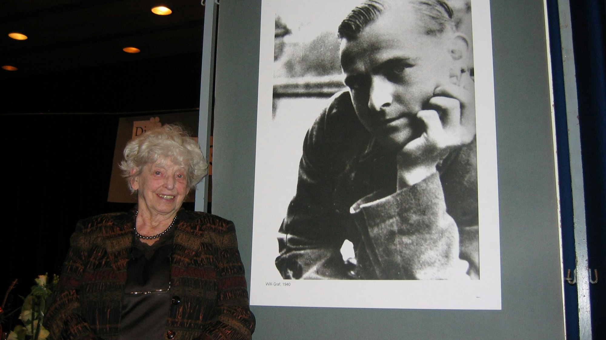 Anneliese Knoop-Graf, Schwester des von den Nazis ermordeten Willi Graf, vor einem Porträt ihres Bruders Willi Graf.
