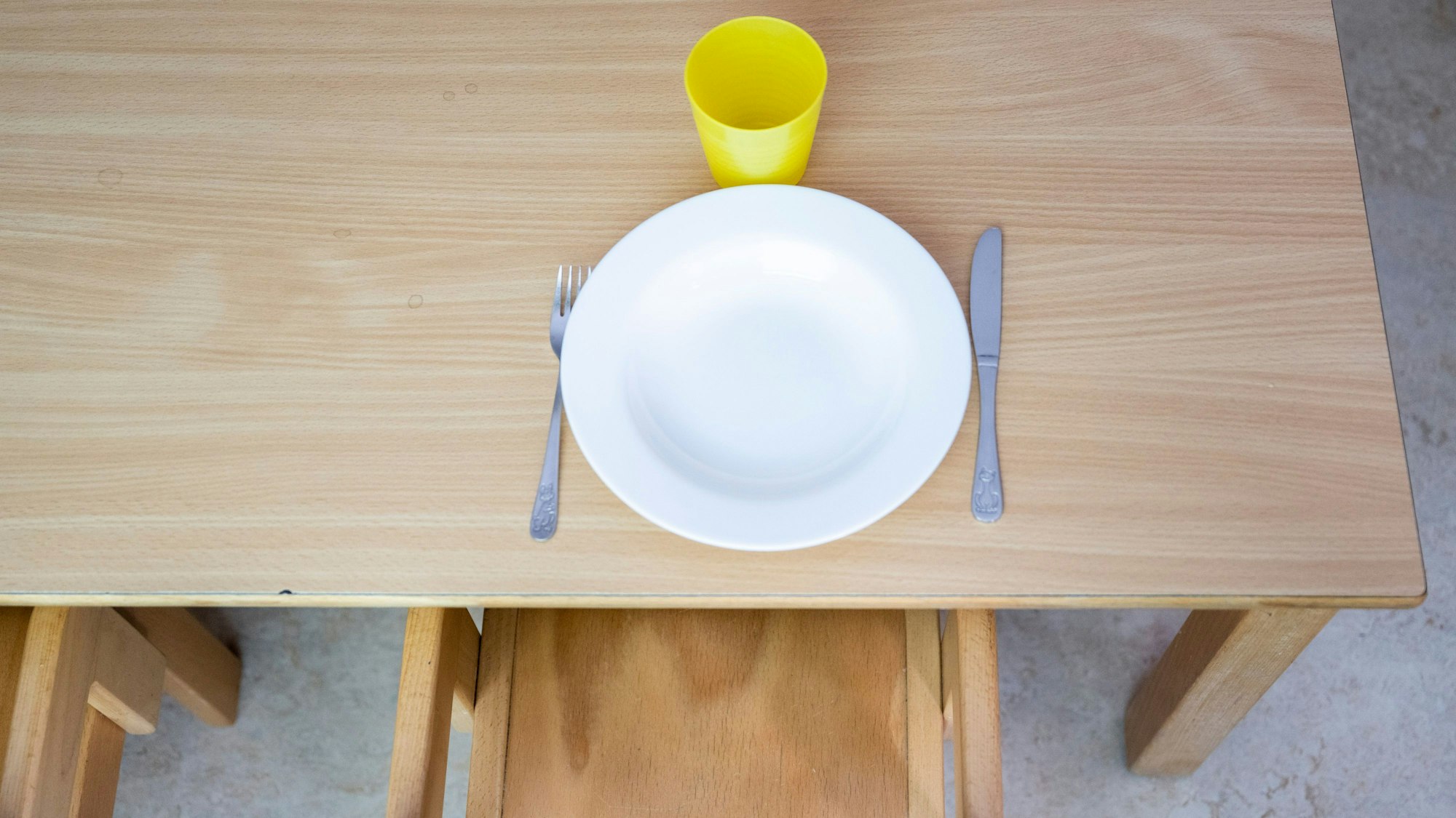 In einer Kita steht ein Teller mit Besteck auf einem Tisch.
