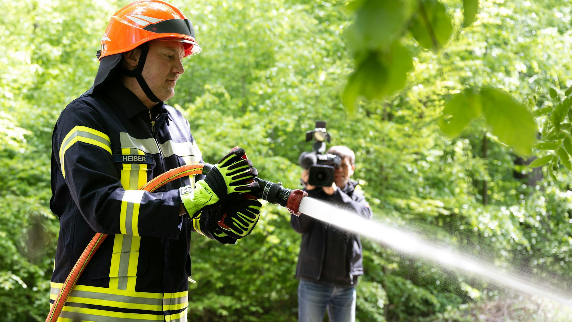 Das Foto zeigt, wie ein Feuerwehrmann einen potenziellen Waldbrand löscht.