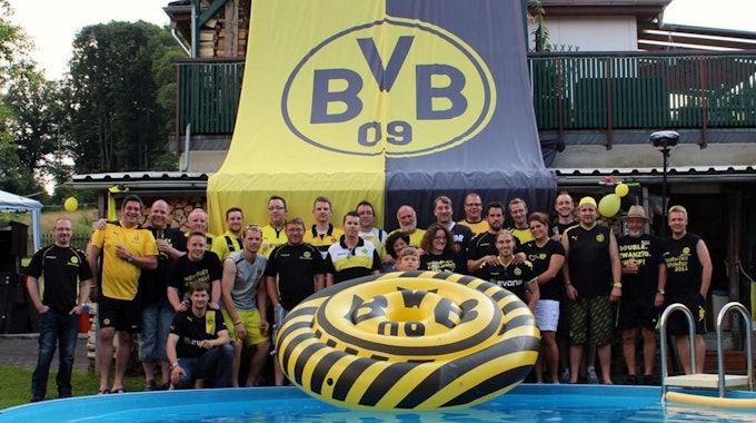 Der Fanklub „Die Gefolgschaft“ mit seinen Mitgliedern vor einer großen BVB-Fahne.
