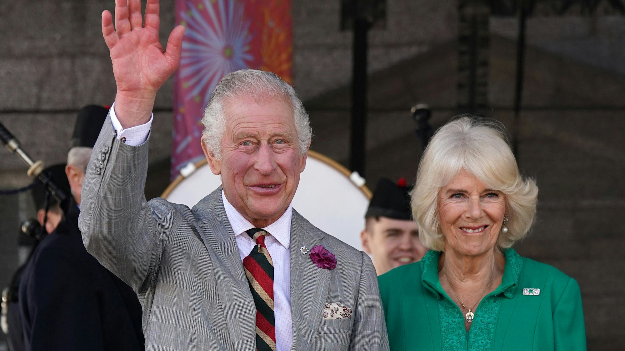 Der britische König Charles III. und die britische Königin Camilla winken und lächeln.