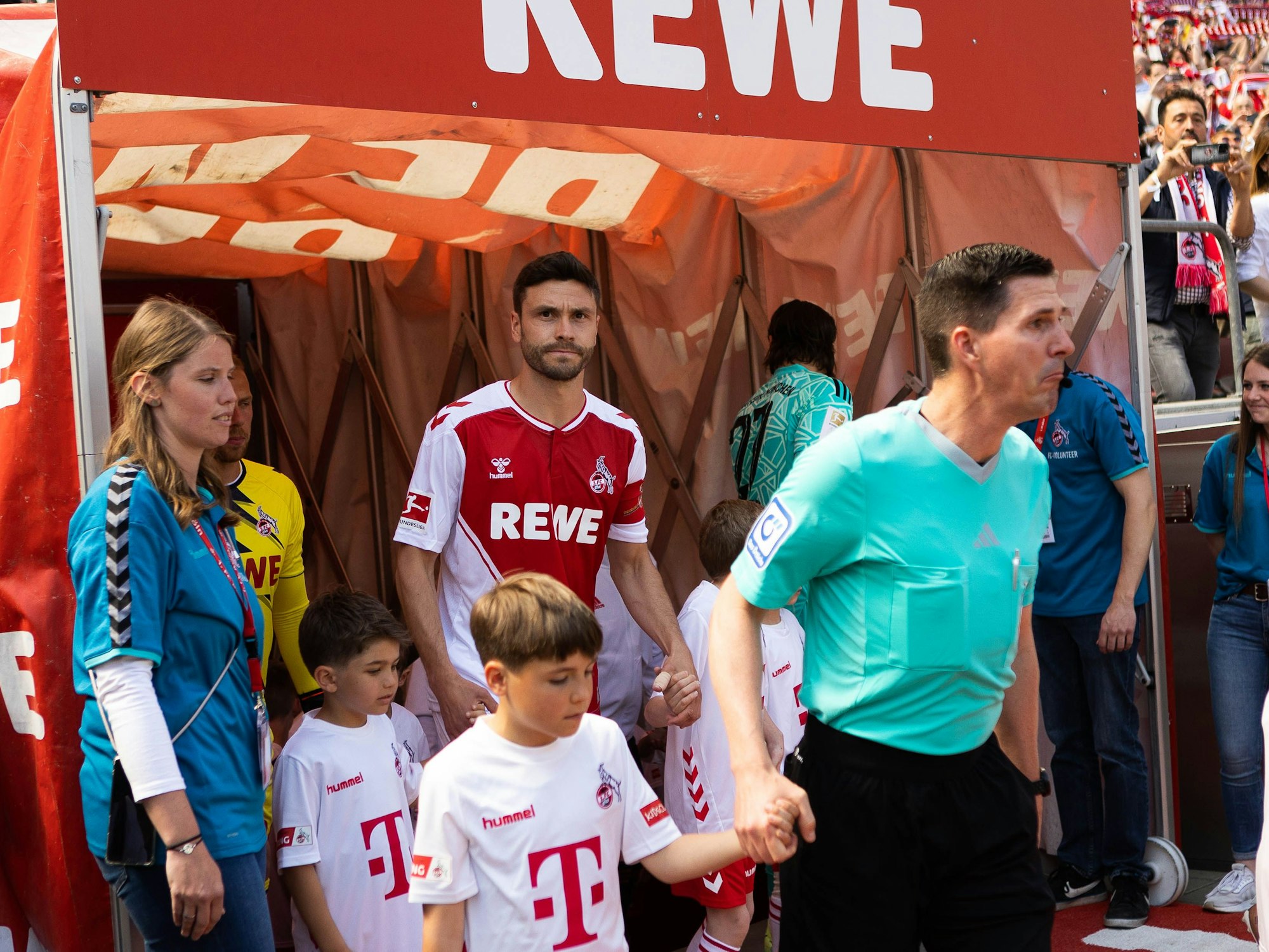 Jonas Hector läuft mit einem Einlaufkind an der Hand aus den Katakomben des Rhein-Energie-Stadions.