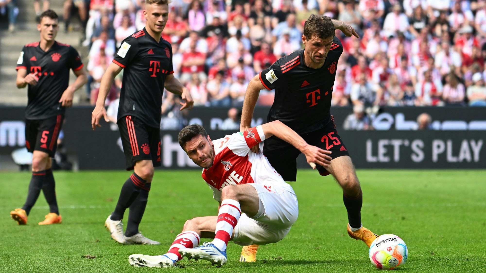 Kölns Jonas Hector (M) und Bayerns Thomas Müller (r) kämpfen um den Ball.