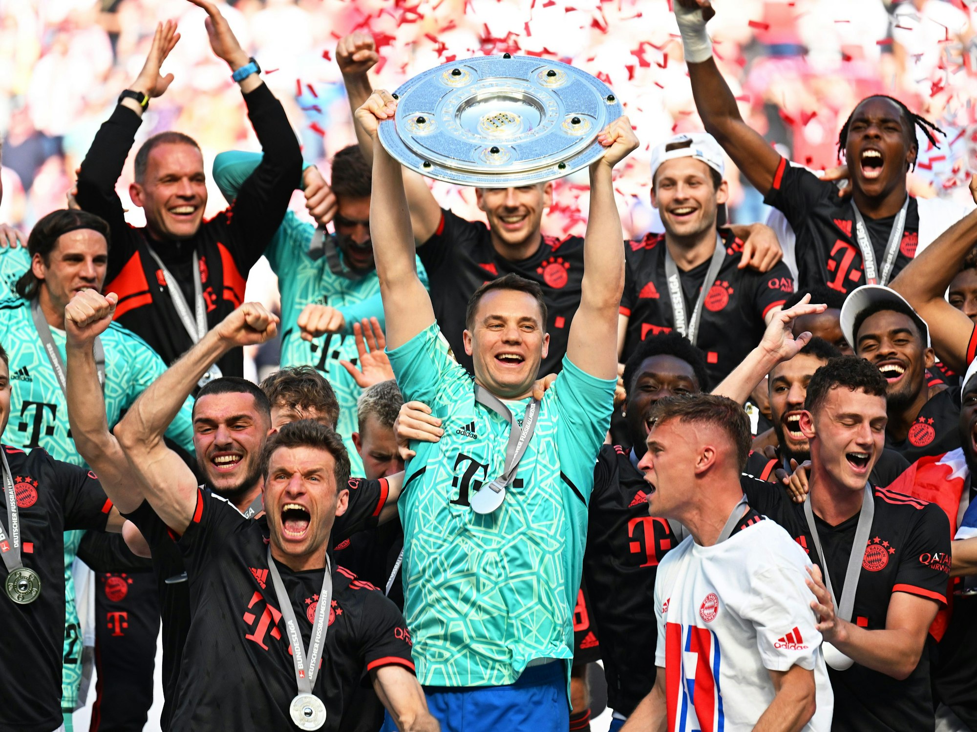Bayerns Torhüter Manuel Neuer (M) hält die Meisterschale hoch während seine Teamkollegen nach dem Gewinn der 33. deutschen Meisterschaft jubeln.