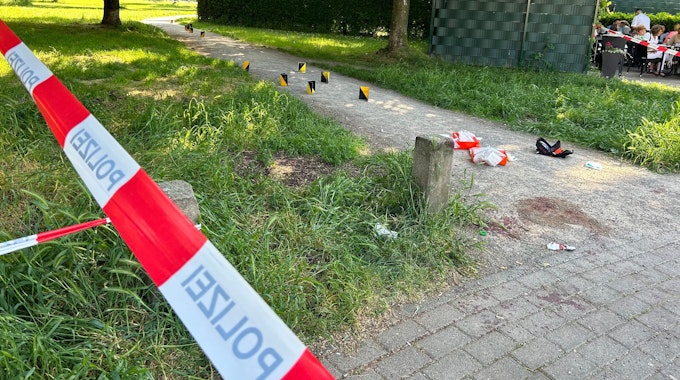 Der Tatort im Böcking-Park in Köln-Mülheim. Auf einem Schotterweg liegt Verbandsmaterial und stehen Tatortmarkierungen.