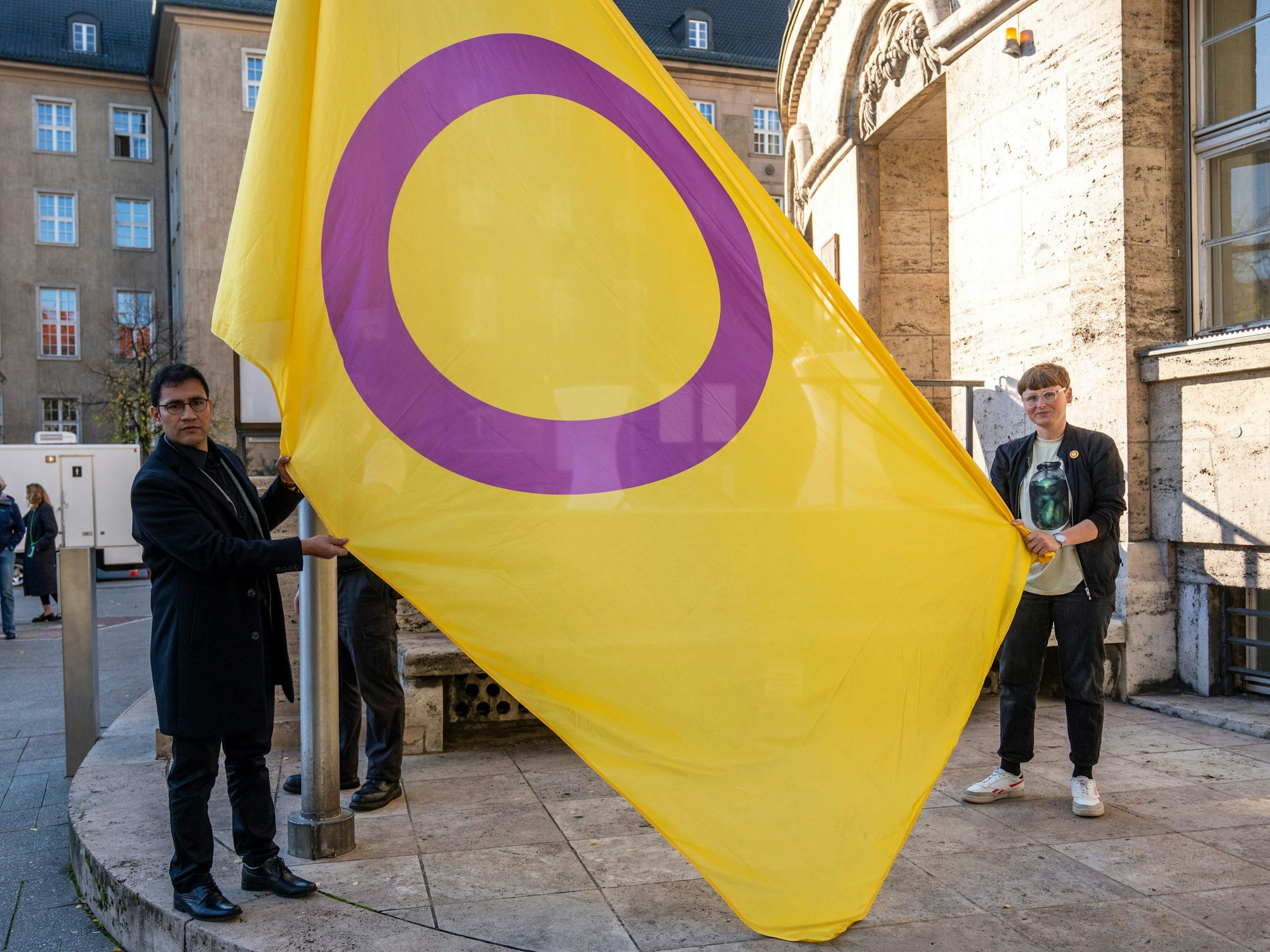 Zwei Personen halten eine gelb-lila Flagge