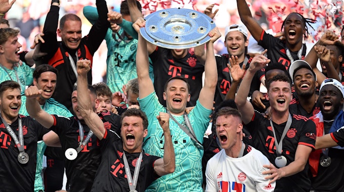Bayerns Torhüter Manuel Neuer hält die Meisterschale, während seine Teamkollegen nach dem Gewinn der 33. deutschen Meisterschaft jubeln.