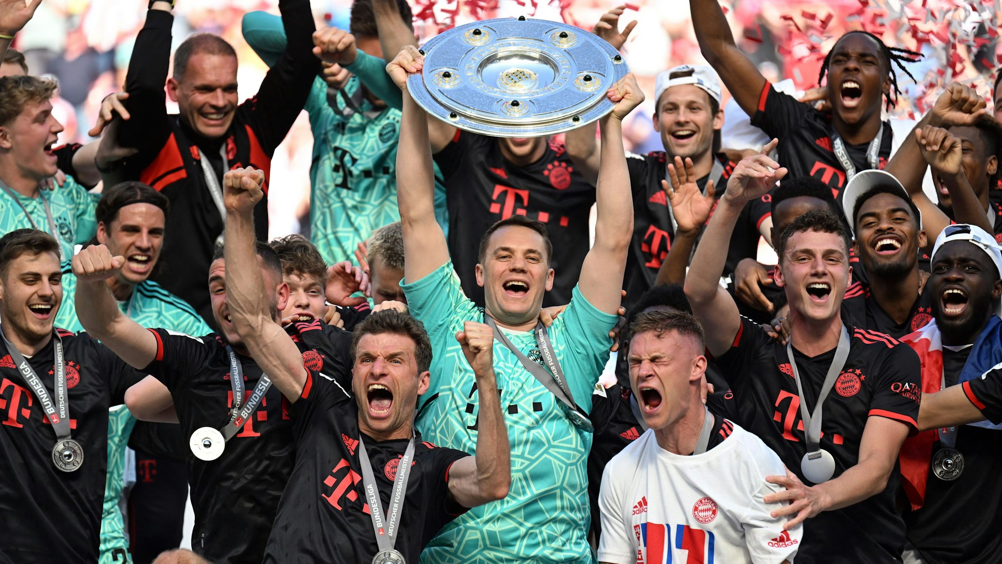 Bayerns Torhüter Manuel Neuer (M) hält die Meisterschale während seine Teamkollegen nach dem Gewinn der 33. deutschen Meisterschaft jubeln.