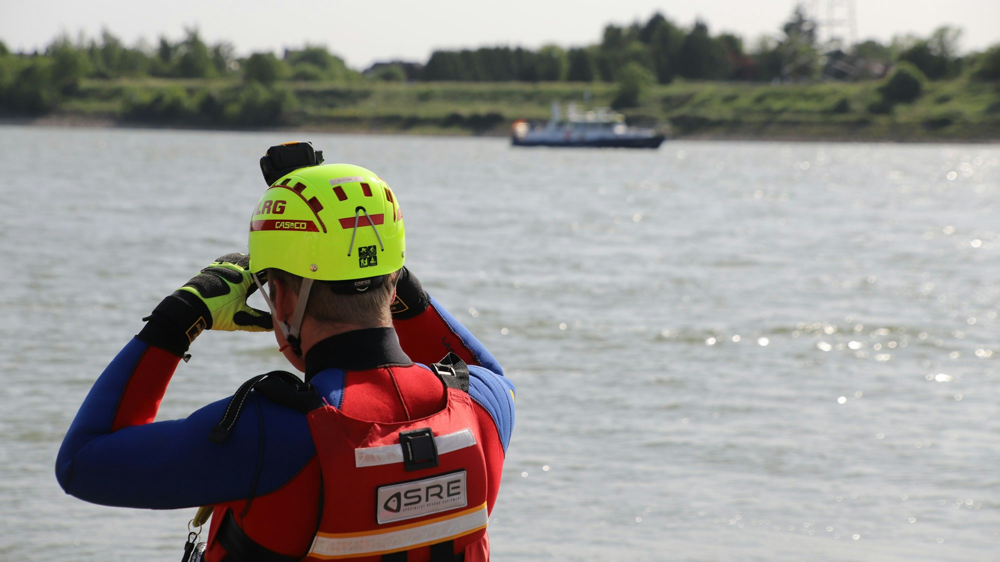 Ein Rettungsschwimmer des DLRG sucht am Rhein nach Personen.