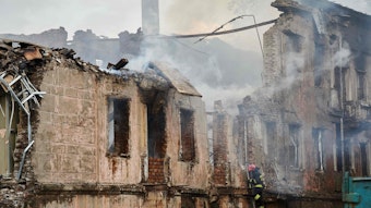 Es ist zu sehen, wie ein Feuerwehrmann das zerstörte Gebäude untersucht.