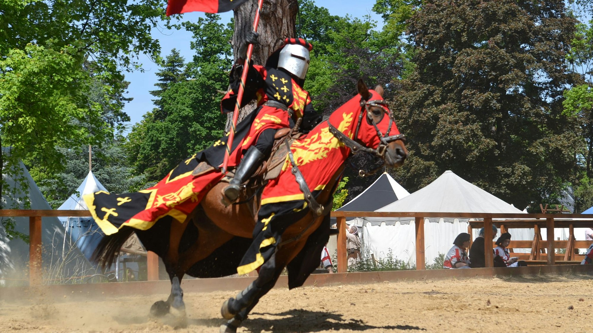 Ein Ritter in vollem Ornat reitet über den Turnierplatz der Burg Satzvey.