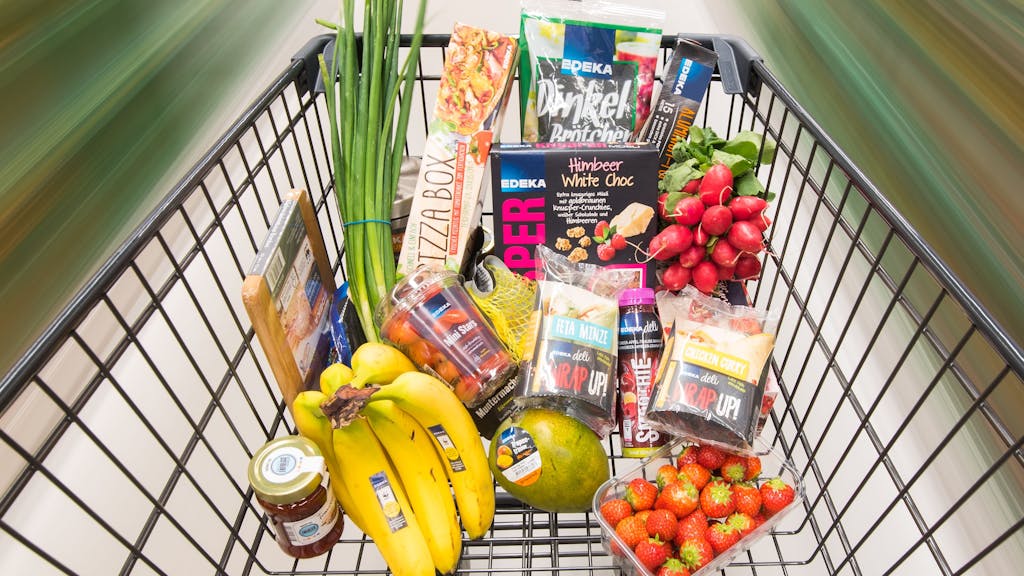 Ein Einkaufswagen mit Edeka-Produkten wird durch einen Supermarkt geschoben