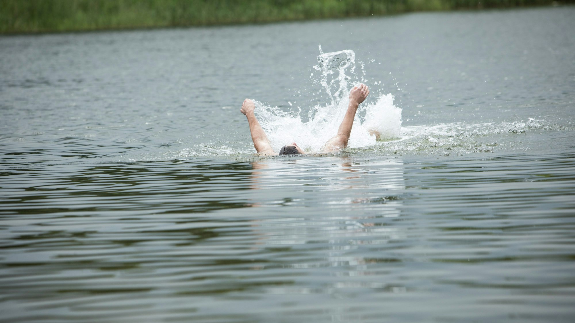 Ein Mann rudert in einem See mit seinen Armen