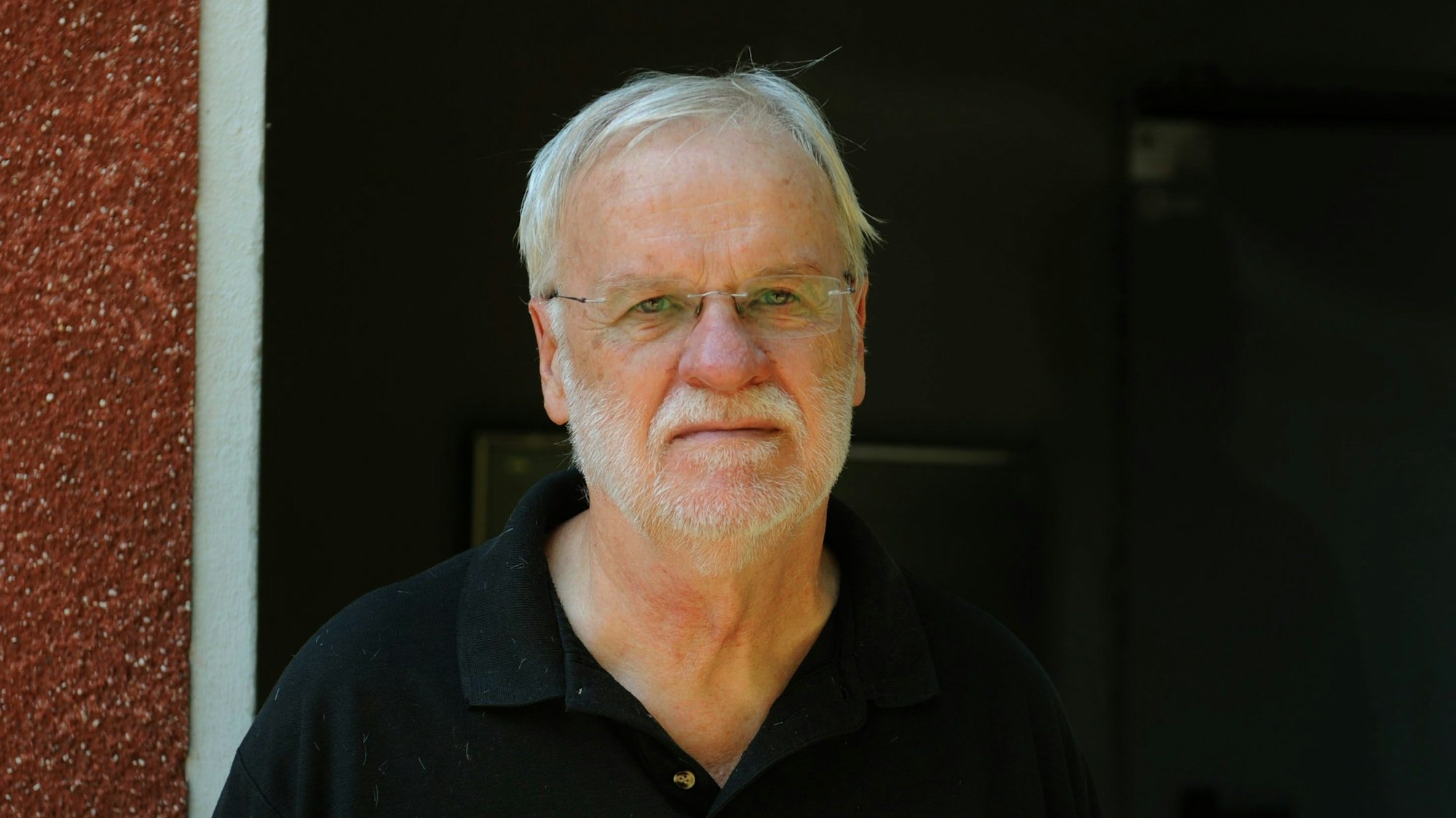 
Walter Buschmann vor einem rot-weiß-schwarzem Hintergrund.