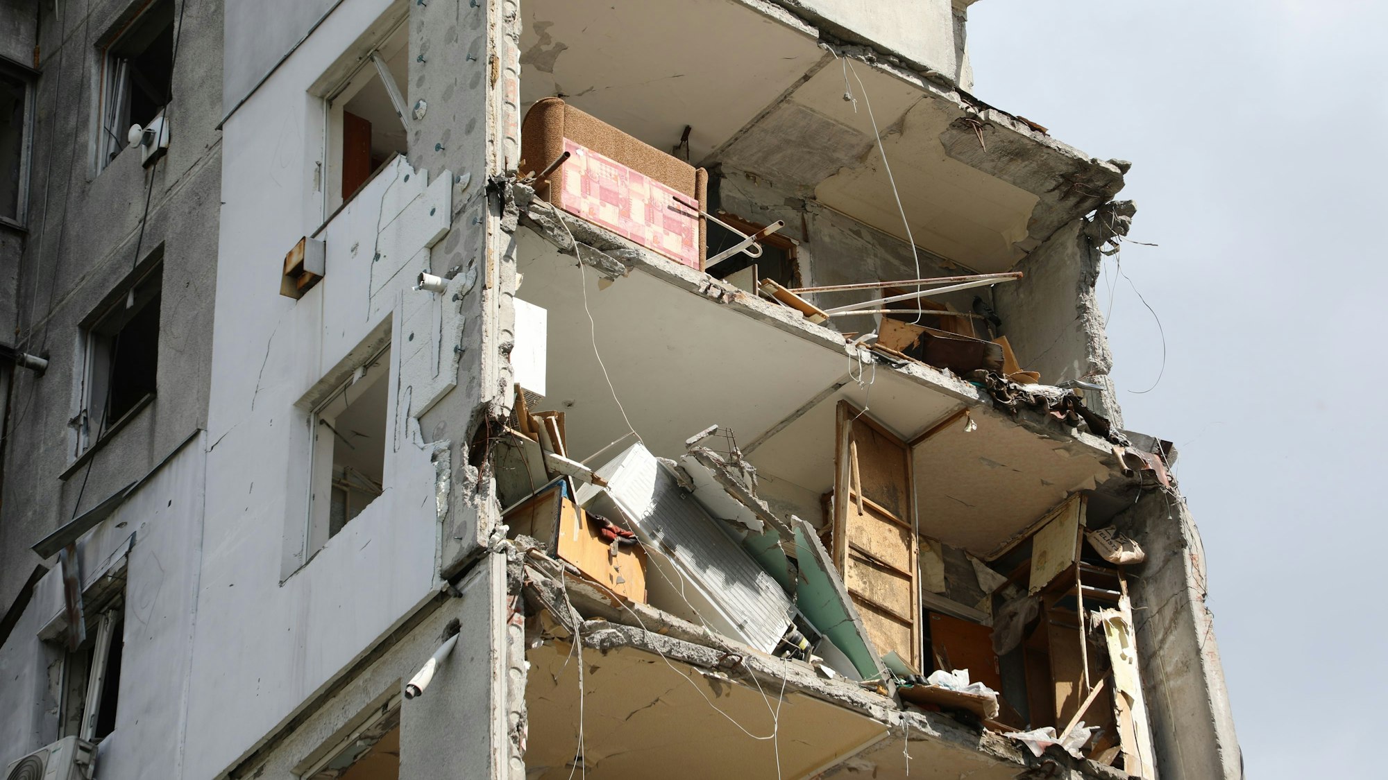 Durch Raketen sind Teile eines Wohnhauses zerstört. Offene Zimmer sind in oberen Stockwerken eines Hochhauses zu sehen.
