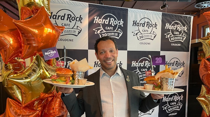 Der Geschäftsführer Uriel Santiago posiert mit Burgern und Pommes.&nbsp;