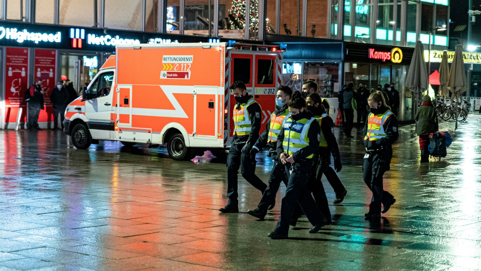 Polizei und Rettungswagen am Dom-Eingang des Kölner Hauptbahnhofs in der Dunkelheit.