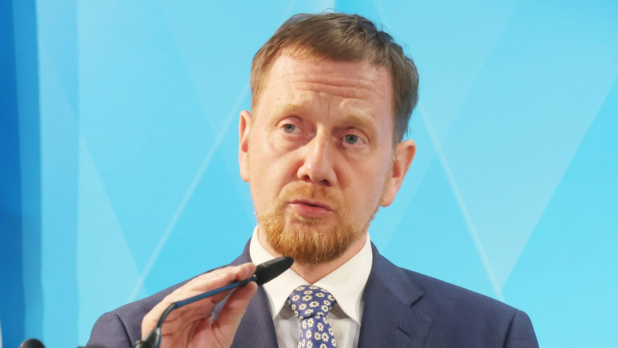 Der sächsische Ministerpräsident Michael Kretschmer (CDU) richtet bei einer Pressekonferenz sein Mikrofon.