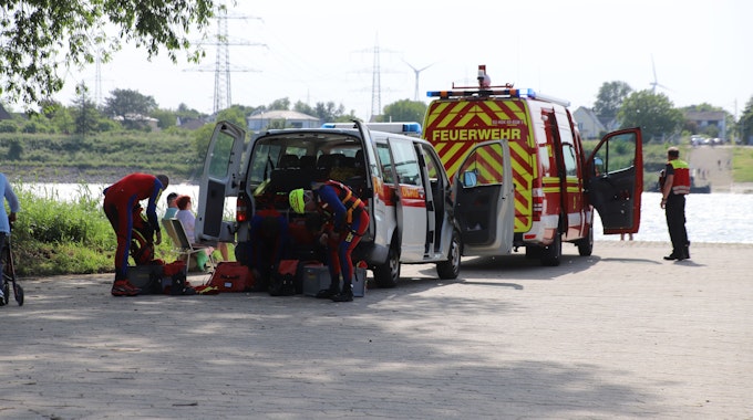 Rettungskräfte ziehen sich bei einem Einsatz an ihren Fahrzeugen um.