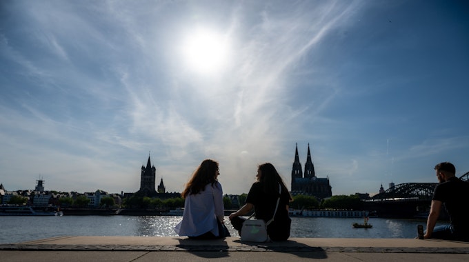 Am Rheinboulevard unterhalten sich junge Frauen im Sonnenschein.