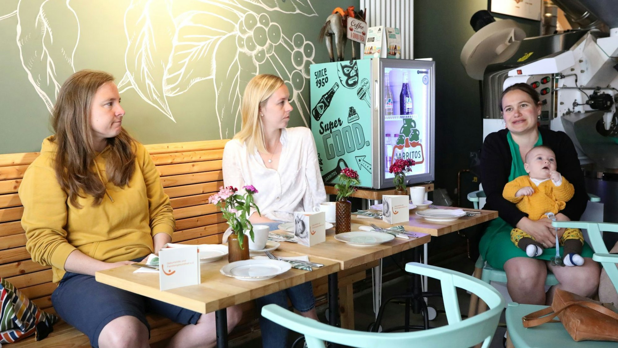 Drei Frauen sitzen an Tischen in der Café-Manufaktur-Rösterei „Taza Azul“, eine hält ihren drei Monate alten Sohn auf ihrem Schoß.