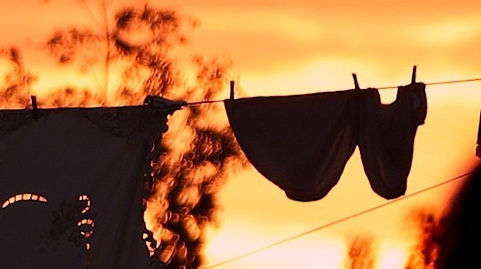Kleidungsstücke hängen bei Sonnenuntergang an einer Wäscheleine (Symbolfoto).