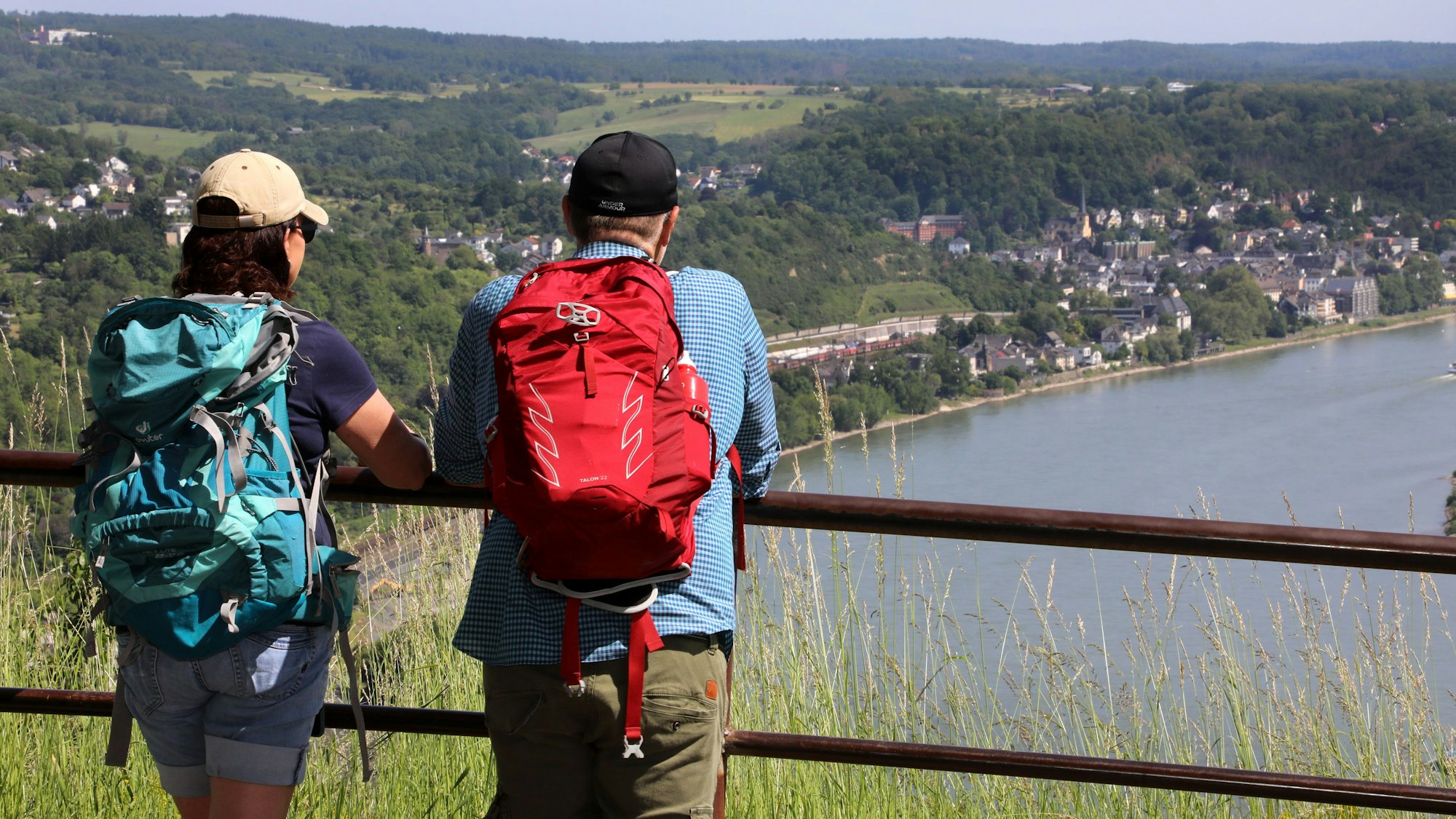Zwei Wanderer schauen von einer Anhöhe auf den Rhein