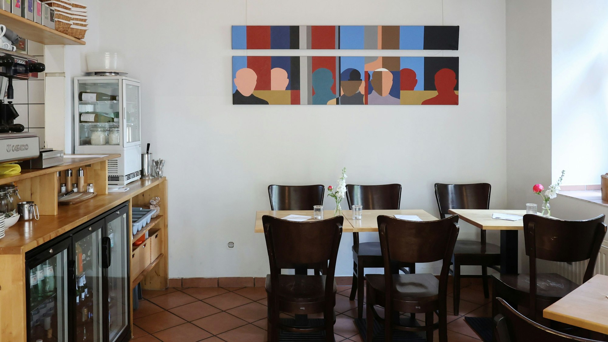 Tische und Stühle in einem Restaurant, bunte Bilder an der Wand
