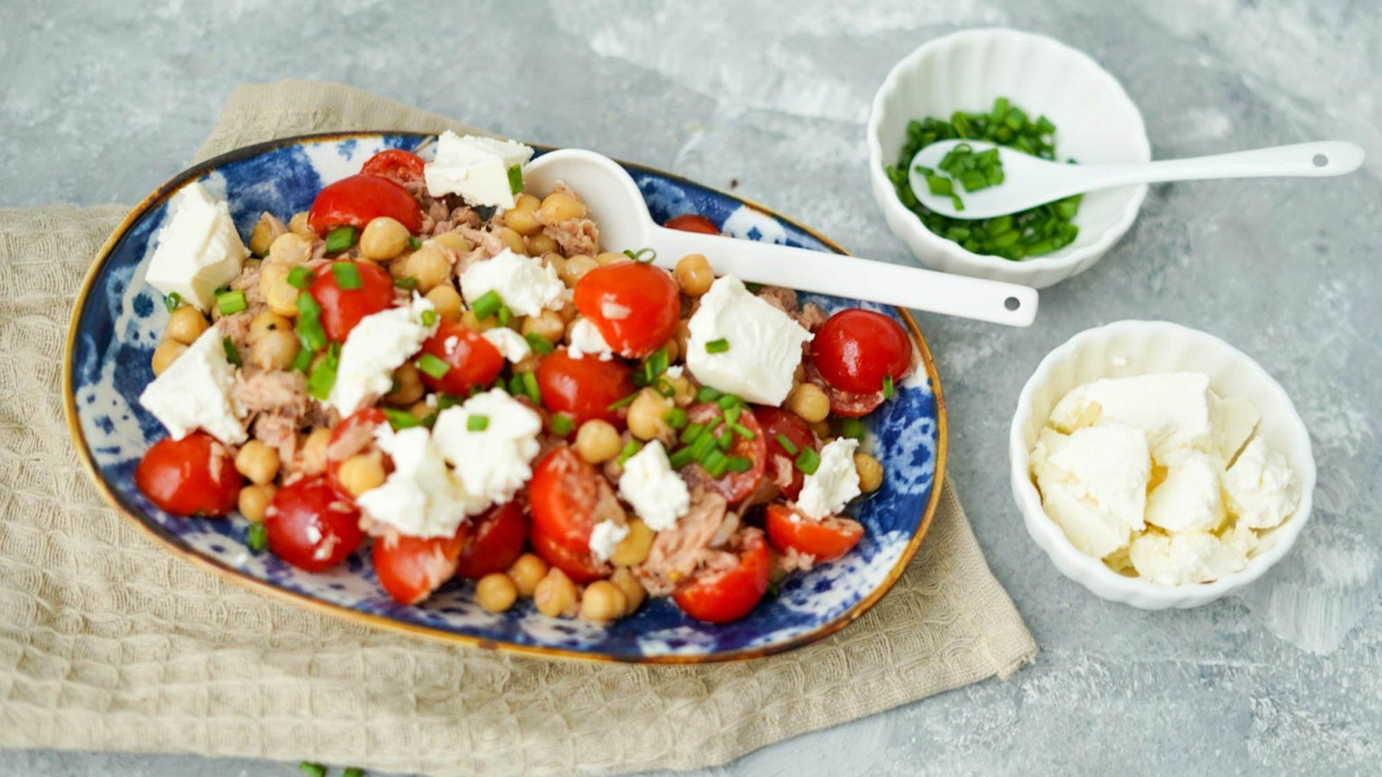 Tomaten, Hirtenkäse und Kichererbsen sind auf einem Teller zu einem Salat zubereitet.