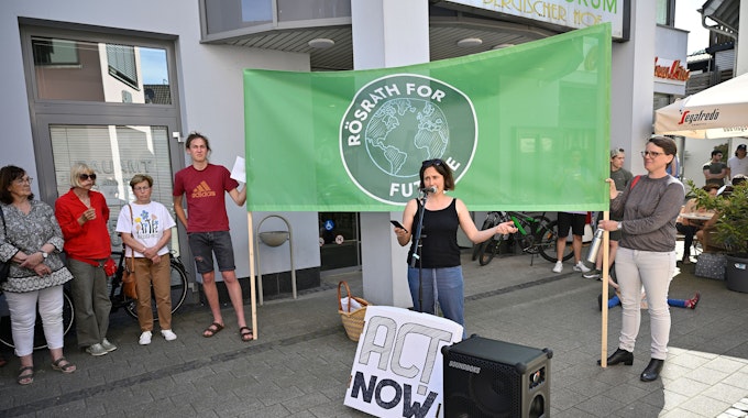 Eine Aktivistin hält eine Rede. Hinter ihr halten zwei Menschen ein Banner mit der Aufschrift „Rösrath for Future“.&nbsp;