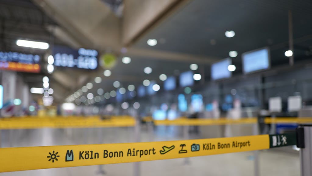 Sperrbänder in gelber Farbe leiten am Flughafen Köln/Bonn die Menschen zu ihren Schaltern.
