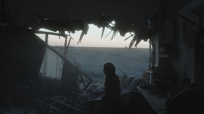 Eine Frau sitzt in den Trümmer eines Hauses.&nbsp;