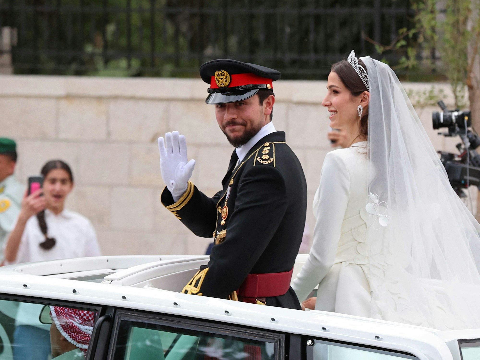 Der jordanische Kronprinz Hussein und die saudi-arabische Rajwa Al Saifwinken am Donnerstag, 1. Juni 2023, während ihrer Hochzeitszeremonie in Amman, Jordanien, den Gratulanten zu.