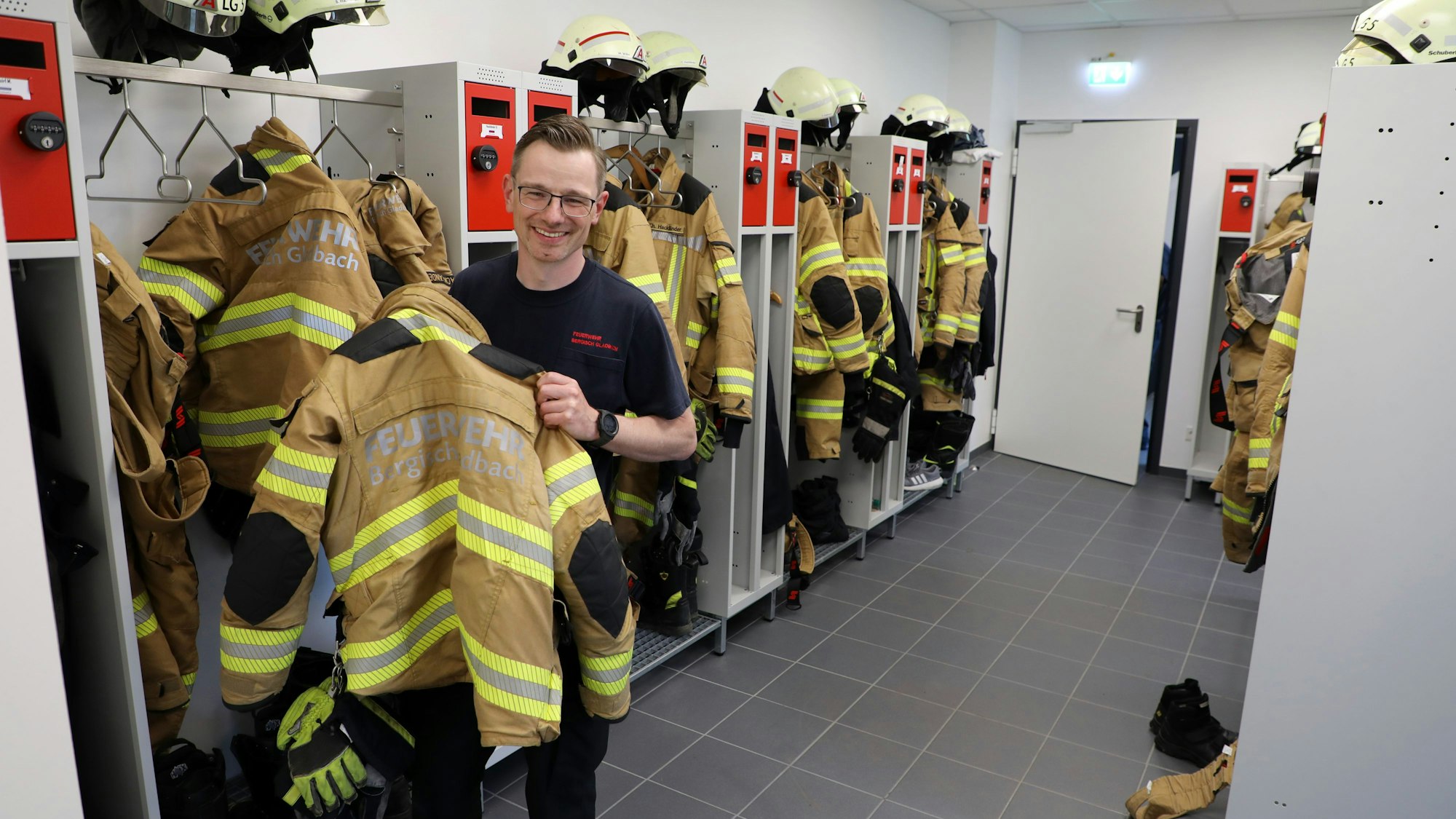 Ein Feuerwehrmann nimmt eine Jacke aus einem Spind in der Umkleide des neuen Feuerwehrhauses in Schildgen.