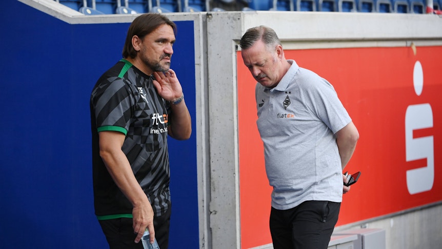 Gladbach-Trainer Daniel Farke (l.) im Gespräch mit Borussia-Manager Roland Virkus. Das Foto zeigt die beiden am 17. Juli 2022 in Duisburg. Farke hat eine Trinkflasche in der rechten Hand.