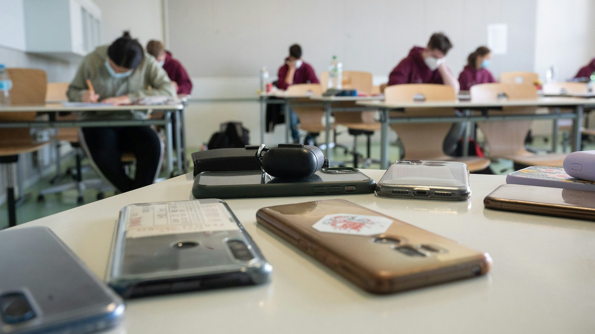 Ausgeschaltete Smartphones liegen in einem Klassenzimmer.