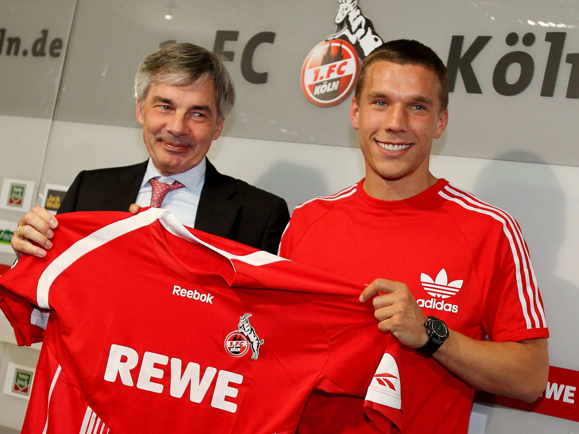 Lukas Podolski neben Manager Michael Maier bei einer Pressekonferenz des Fußball-Bundesligisten 1. FC Köln in Köln sein neues Trikot.