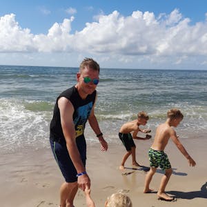 Ein Mann spielt am Strand mit seinen Kindern.