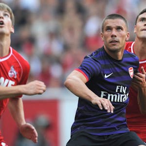 Lukas Podolski (M.) vom FC Arsenal wehrt sich im August 2012 im Testspiel gegen Jonas Hector (r.) vom 1. FC Köln, Lukas Kübler (l.) schaut zu.