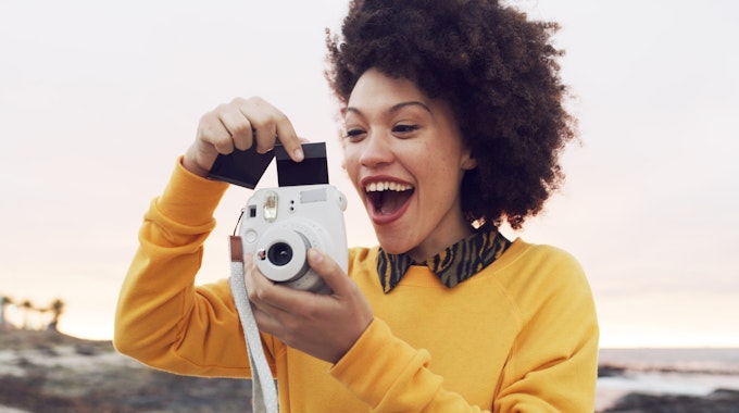 Frau hält Polaroid Kamera mit Bild in den Händen 