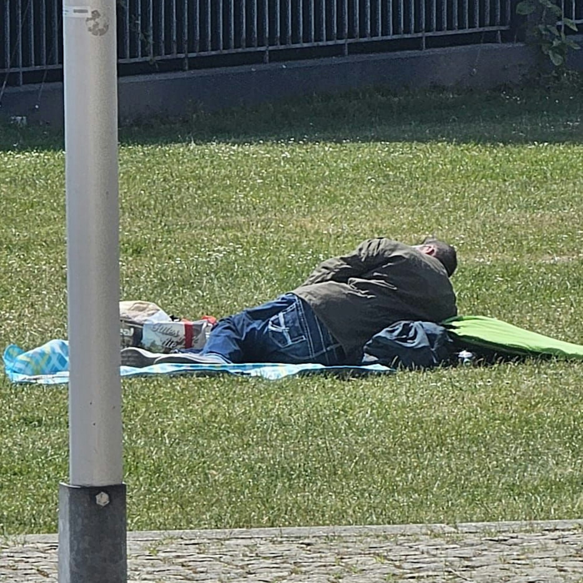 Camper vor dem Landtag: Ein Mann liegt auf einem Liegetuch auf dem Rasen, um ihn herum einige Utensilien.
