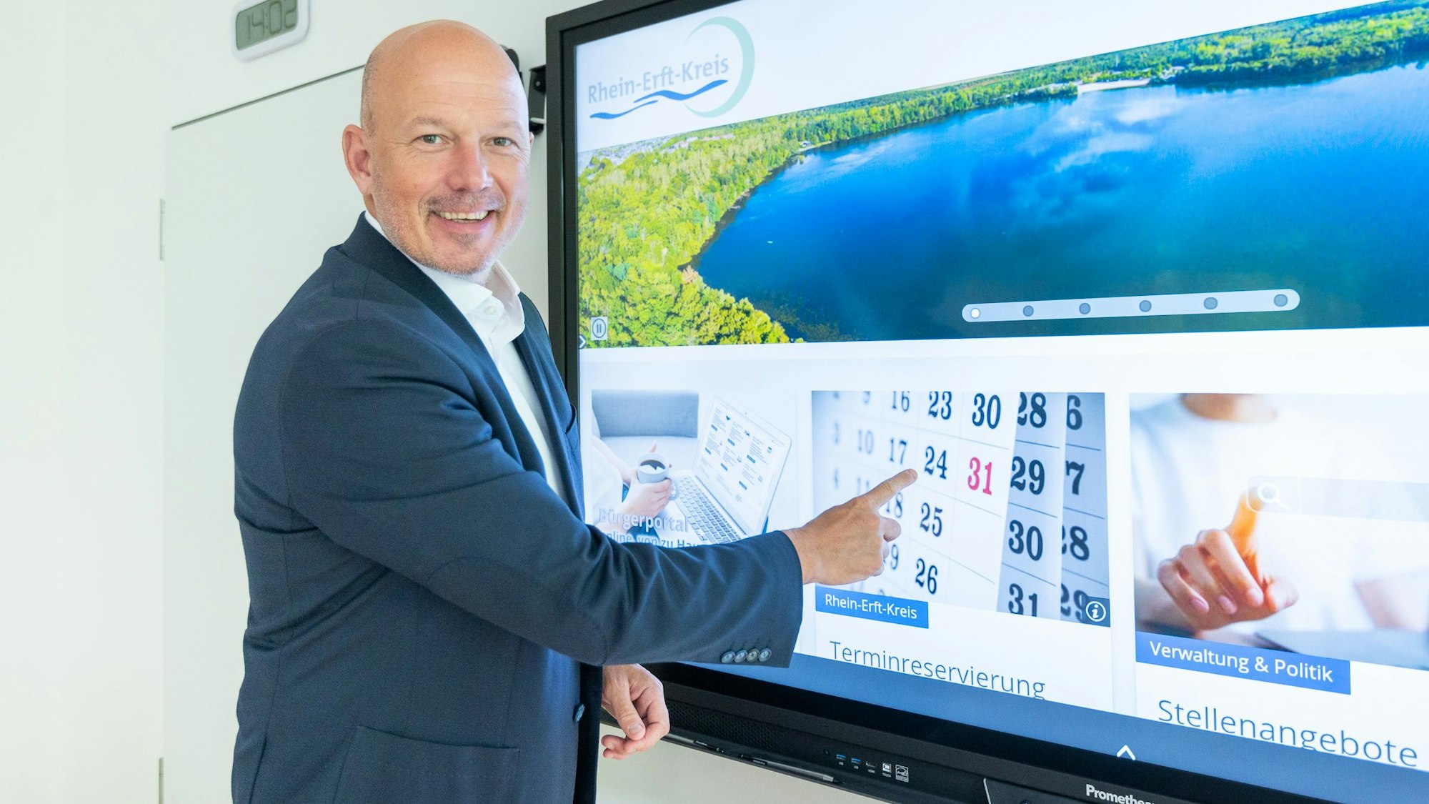 Das Foto zeigt Landrat Frank Rock. Er zeigt auf die Startseite der neuen Homepage des Rhein-Erft-Kreises auf einem großen Monitor.