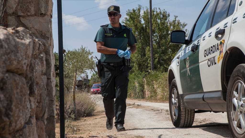 Ein Mitglied der Polizeieinheit Guardia Civil geht zwischen einem Einsatzfahrzeug und einer Mauer entlang, hier im August 2019 auf Mallorca.