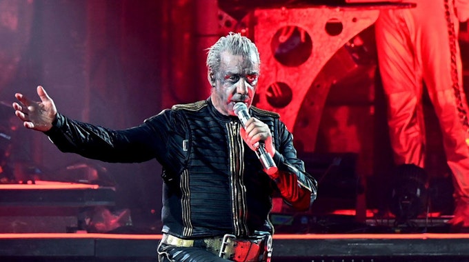 Till Lindemann, Frontsänger von Rammstein, steht bei einem Konzert auf der Bühne. Im Hintergrund ist rotes Licht zu sehen.