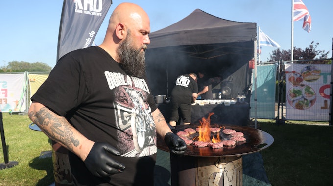Mann grillt Burger am offenen Feuer