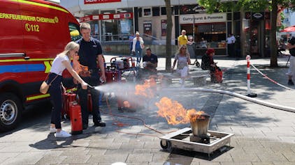 Eine Frau löscht mit einem Feuerlöscher einen künstlichen Brand