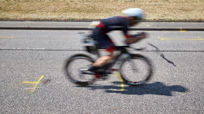 Tragödie bei Ironman-EM in Hamburg: Ein Triathlet fährt auf dem Rad an der Unglückstelle auf dem Gaueter Hauptdeich vorbei.