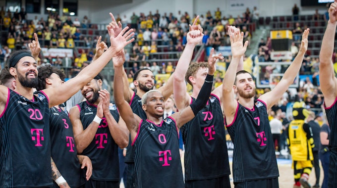 Jubel bei den Baskets: Mit dem Sieg in Ludwigsburg haben sie sich für die Play-off-Finals qualifiziert. Spieler stehen mit augebreiteten Armen und glücklichen Gesichtern nebeneinander.